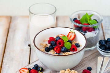 Bowl with vegan granola with fresh ripe organic berries, plant milk, mint. Concept of dieting, detox, tasty simple super food, healthy low calories breakfast. Wooden background, close up