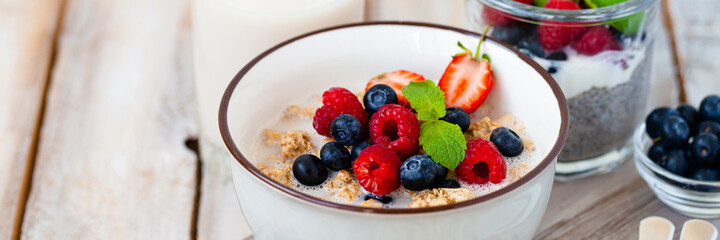 Bowl with vegan granola with fresh ripe organic berries, plant milk, mint. Concept of dieting, detox, tasty simple super food, healthy low calories breakfast. Wooden background, close up. Banner
