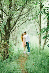 Obraz premium Young lovely couple kiss each other behind the trees