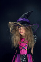 A girl dressed as a witch and a wide-brimmed hat for Halloween.