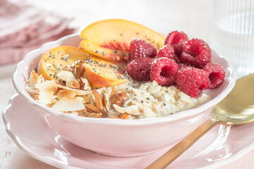 Porridge oatmeal with raspberries, peaches and nuts for breakfast. Healthy vegetarian food concept.