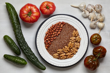 A background of fresh vegetables on a wooden table and with a plate of nuts