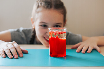Lava lamp, science experiment with water, food coloring, oil and aspirin doing by school girl. Step...