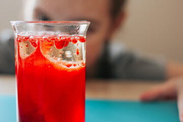 Lava lamp, science experiment with water, food coloring, oil and aspirin doing by school girl. Step...