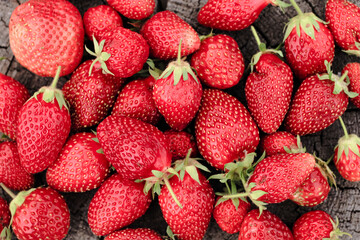 Heap of strawberries on natural wooden background. New fresh harvest, summer, summertime, garden concept. Organic gresh natural diet eco friendly food. 