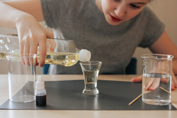 Lava lamp, science experiment with water, food coloring, oil and aspirin doing by school girl. Step...
