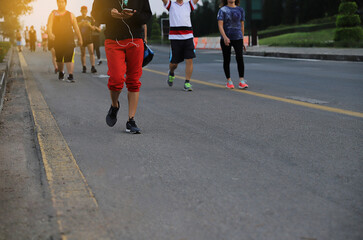 A Man  Holding Cell Phone And Listening Music While Jogging On park with group of people.