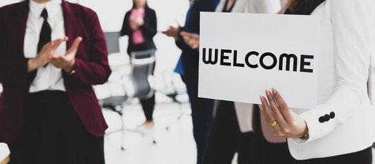 Group of businesspeople joins together greeting and hold welcome words for a sign of happiness and...