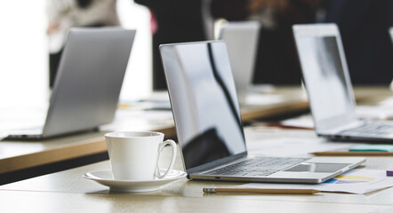 Selective focus on working desk, group of unrecognizable businesswomen standing together in office at breaking time. Female employee teamwork taking with relax in blur background