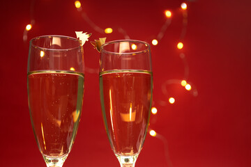 Closeup of pair of wineglasses against red background and glowing golden lights