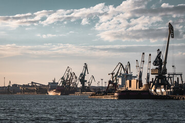 Fototapeta na wymiar Rusty Klaipeda harbor cranes on cloudy sky background. 