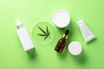 Cannabis cosmetic products. Natural cosmetic. Cream, soap, serum and others. Flat lay image on green background.