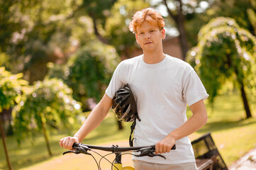 Guy with bike and helmet standing resting