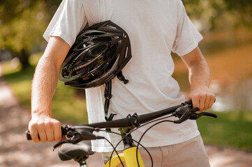 Male hands holding helmet and bike