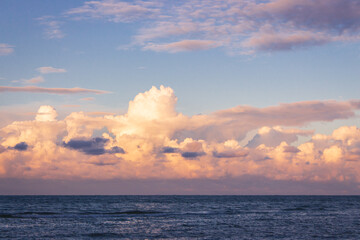 Scenic sunrise over the sea. Morning dusk on island. Dramatic morning sky with clouds. Summer seascape in twilight. Calm sea and idyllic sunrise. Golden sunsine through clouds over sea.