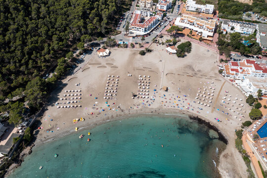 Top down aerial photo of the Spanish island of Ibiza showing the beautiful beach front and hotels on and the beach at Cala Llonga in the summer time in the Balearic Islands, Spain