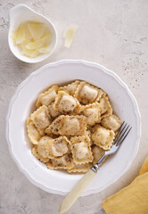 Closeup of tasty appetizing ravioli with fresh black pepper and cheese on white plate.