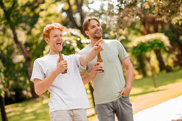 Two friends with beer having fun in park