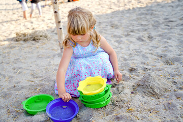 Little preschool girl playing with sand toys on the beach. Cute happy toddler child on family vacations on the sea. Active child having fung on Baltic Sea. Outdoor activity for children