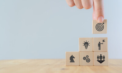 Business, success, leadership and achievement concept. Man hold wooden cube with goals and success icon and other icon with the element process to achieve; strategy, solution, teamwork, leader, idea.