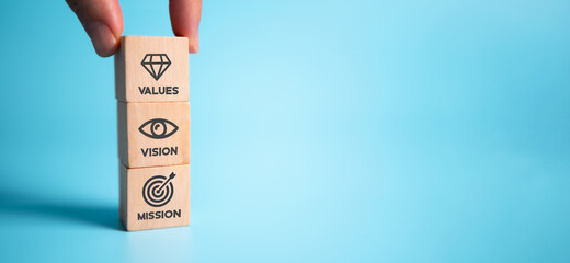 Mission vision values concept icon on wooden cubes stacked vertically on beautiful blue background....