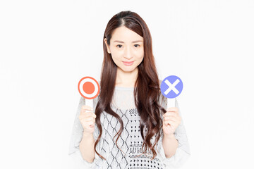 OKとNGのプラカードを持って立っているカジュアルな服装の女性