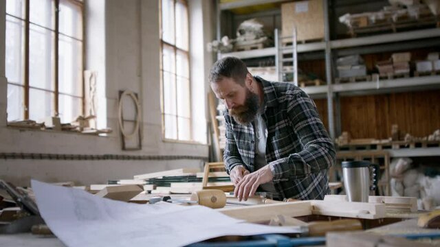 Male carpenter sketching desing of his product, looking at camera. Small business concept.