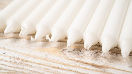 New white candle set on wooden table. Long wax candles. Set of traditional candles. Lots of new long white wax candles