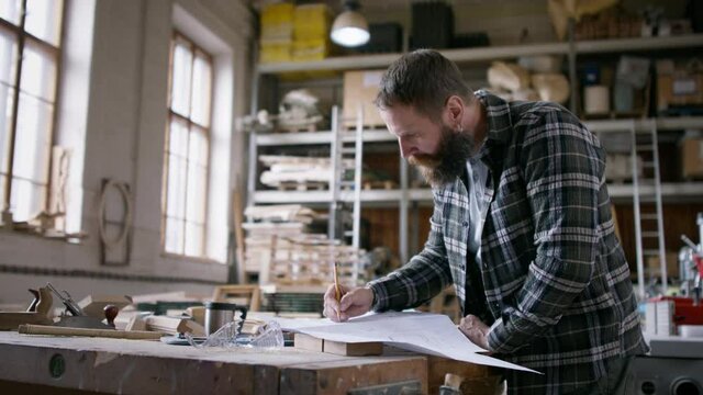 Male carpenter sketching desing of his product. Small business concept.