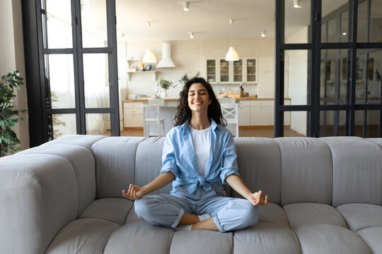 Stress Management. Peaceful Young Lady In Casual Wear Meditating With Closed Eyes On Couch At Home