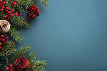 Christmas border with paper decorations, fir branches and berries on dark turquoise background.