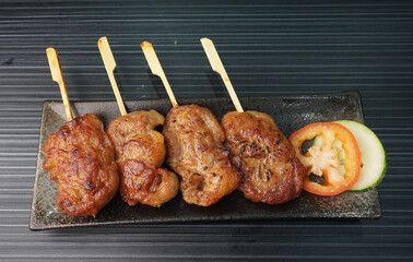 thai bbq grilled tender pork chop meat with sauce in plate on dark grey wood table asian dim sum...