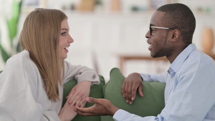 Obraz premium Interracial Couple having Conversation while Sitting on Sofa