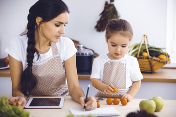 Happy woman and her daughter are searching for new recipes for a delicious family feasting. Christmas, New year, Thanksgiving, Anniversary, Mothers Day. Healthy meal cooking concept