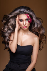 An attractive beautiful woman with natural curly shiny hair poses. A lot of hairstyle with the effect of beach curls.