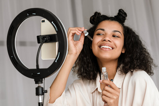 Black woman applying beauty products while taking selfie footage