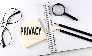 Word PRIVACY on the sicker on notebook with pencils,magnifier and glasses