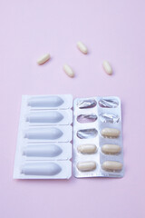 Gynecological medicines for women's health in form of suppository, capsules on pink background.