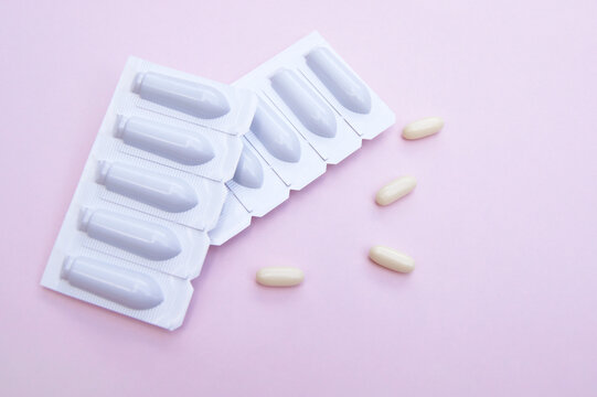 Gynecological medicines for women's health in form of suppository, capsules on pink background.