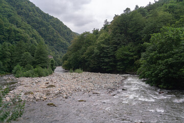 The mountain river flows rapidly over the rocks towards