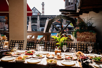 wooden table served with plates with salad and snacks on the open terrace