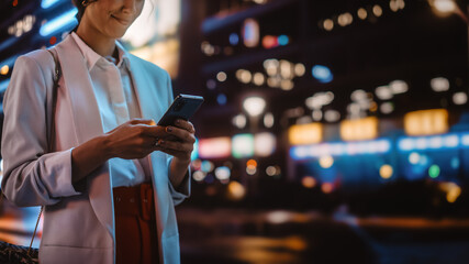 Anonymous Female Using Smartphone Walking Through Night City Street Full of Neon Light. Woman...