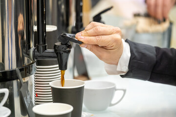 Businessperson pouring coffee into cup