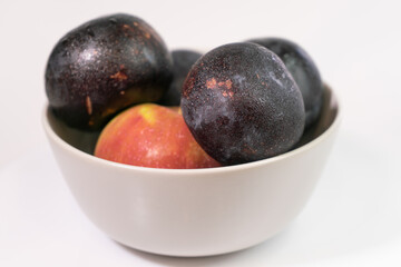 Fresh fruits in a light ceramic plate on a homogeneous background for a healthy vegetarian diet
