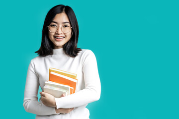 Young Asian student girl holding books isolated blue screen.
