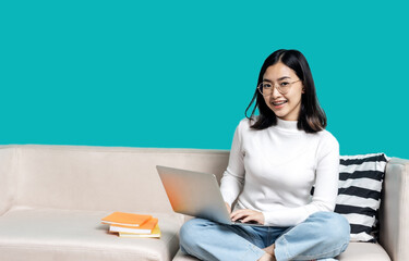 Beautiful Asian caucasian girl sitting on the sofa at home use a laptop. Education and work.