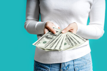 Asian woman happy satisfied holding bunch of money banknotes and looking at camera isolated over blue background