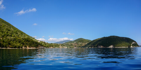 Blue clear calm Ionian Sea wide panorama. Water with nice reflection and scenic green hills coast. Nature of Lefkada island in Greece. Summer vacation idyllic travel destination