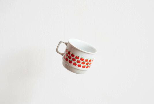 Mid-century modern porcelain mug with apple pattern isolated, flying on white background