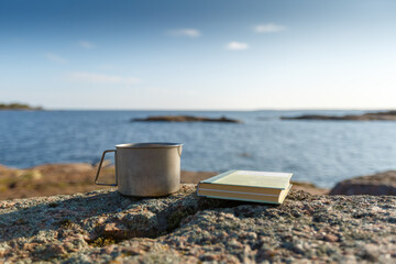 Fototapeta na wymiar Book with a mug on the background of the sea. Objects in focus. The background is blurred.